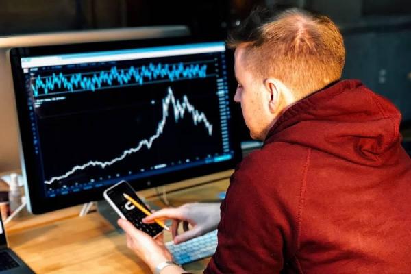 Un inversor frente a una computadora realizando análisis de precio de un activo.