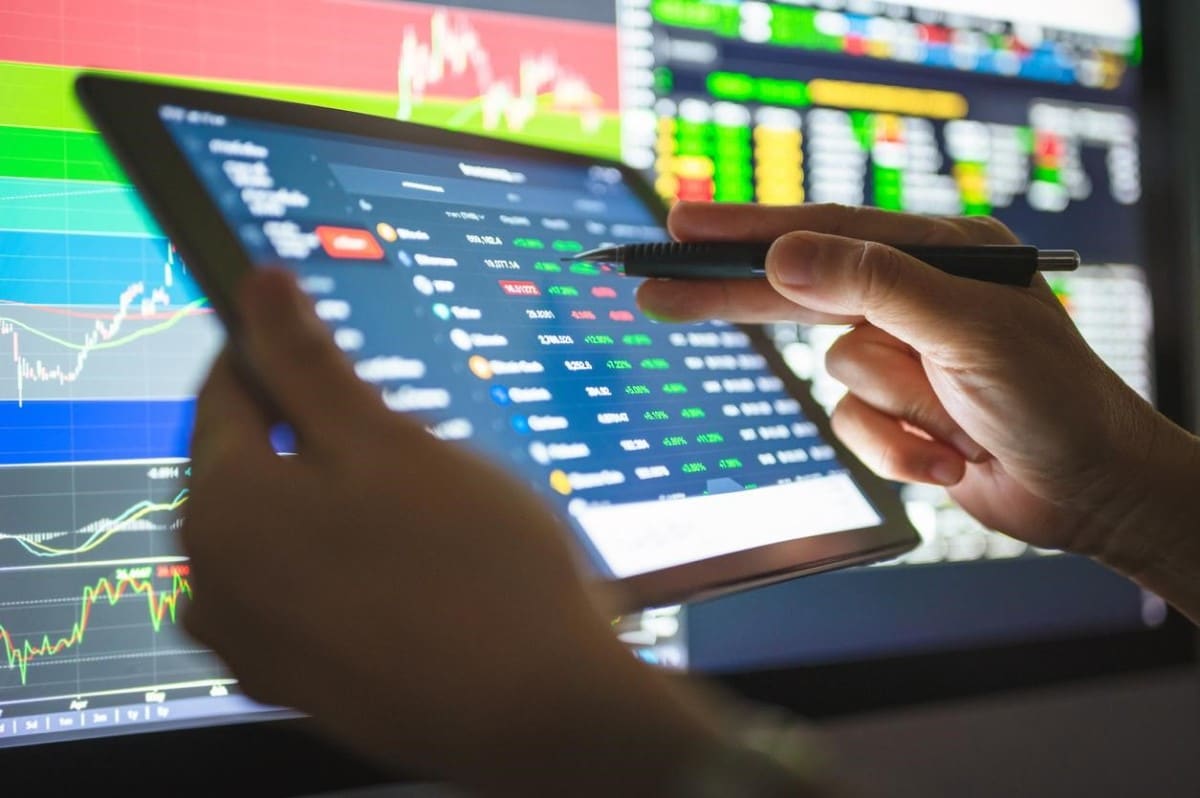 Un trader revisa precios de criptomonedas en su tablet para aprender a invertir en ellas.