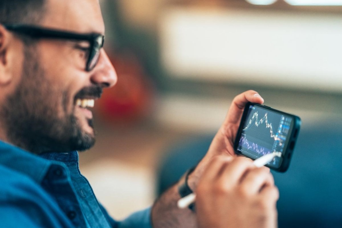 Trader feliz de saber cómo interpretar gráficas de precios de criptomonedas en su celular.