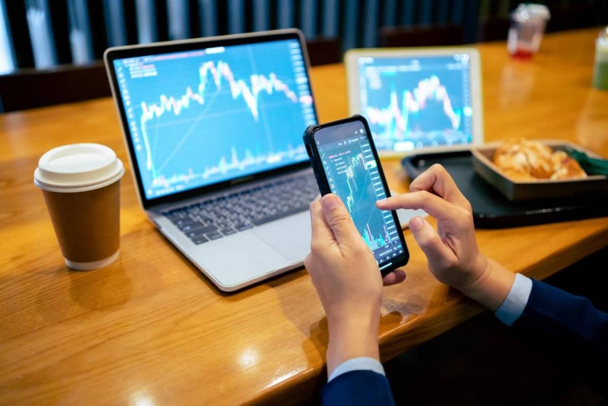 Inversor analiza en su celular tendencias de las criptomonedas más populares.