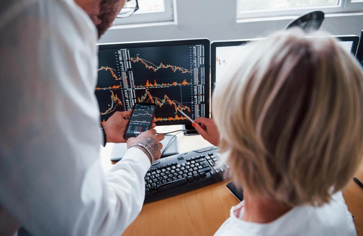 Dos personas analizan gráficos de tendencia y conversan sobre la estrategia DCA.