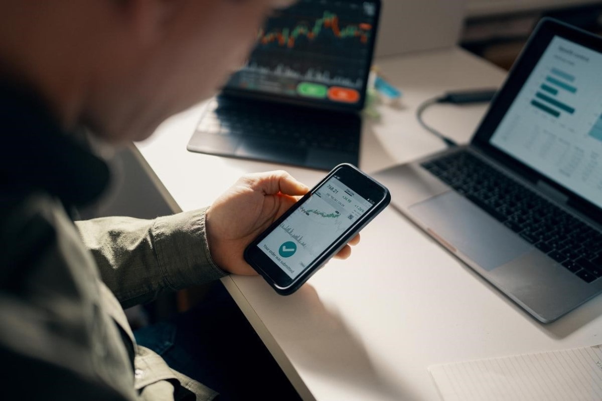 Un hombre analiza en su celular gráficos de divergencias en trading.