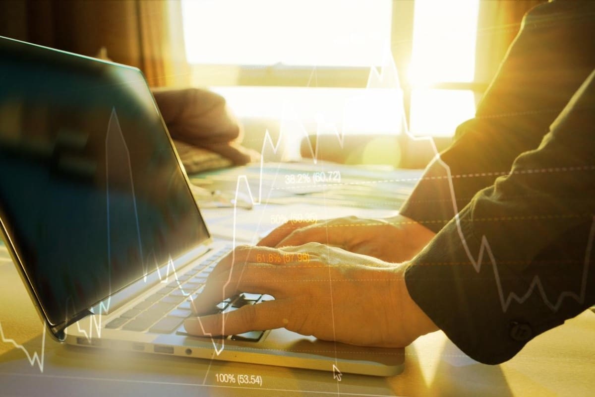 Trader investiga en su laptop las aplicaciones del indicador Fibonacci en trading.