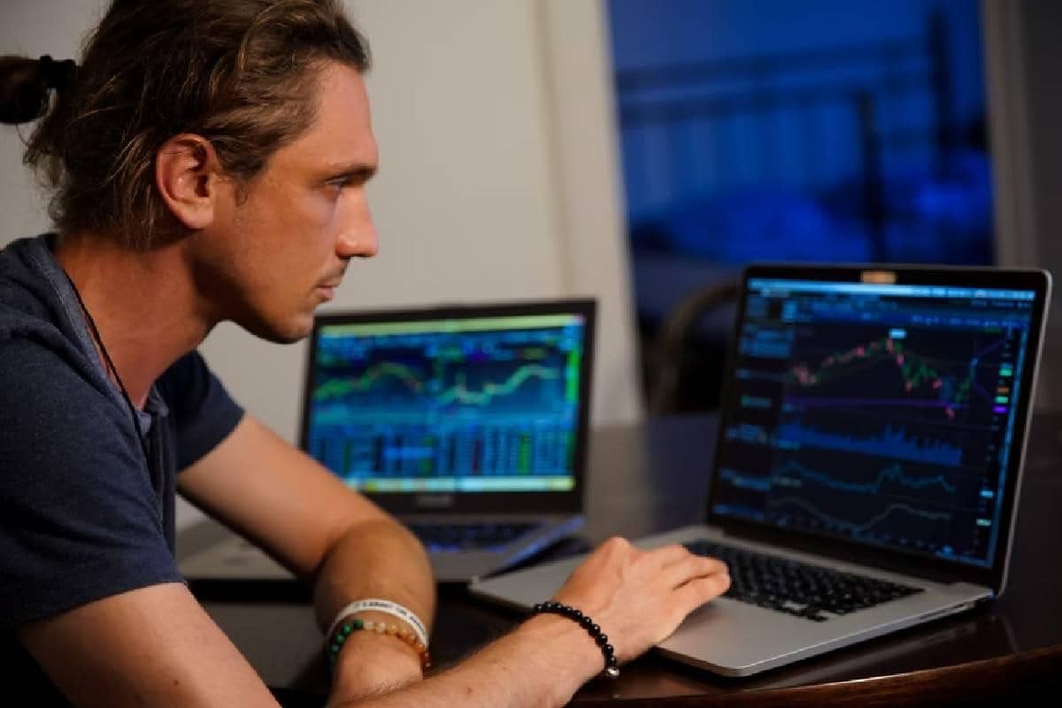 Un joven en el computador revisando mercados financieros y haciendo trading.