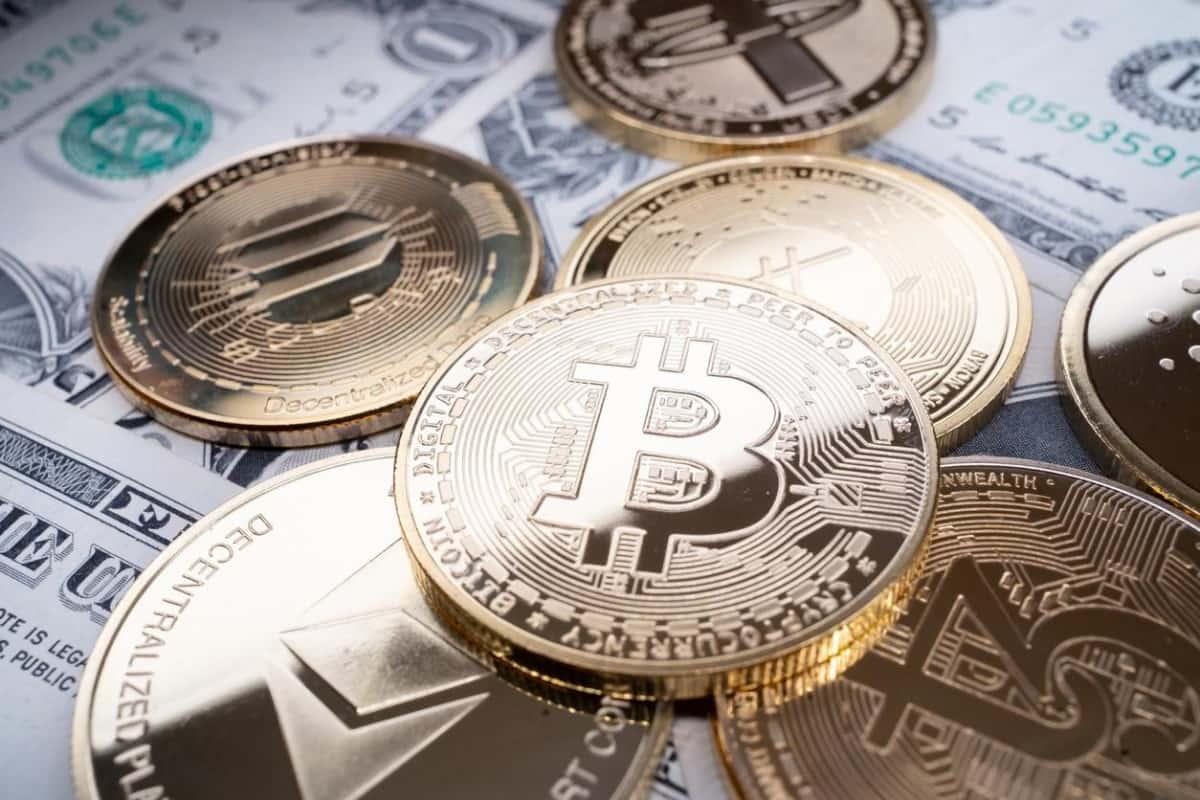 Varias criptomonedas sobre billetes de dólar. Estas son uno de los instrumentos de inversión más comunes en Chile.