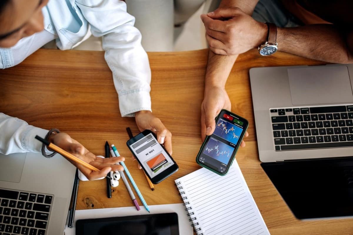 Traders analizan gráficos de tendencia en sus celulares para sus inversiones en Argentina.