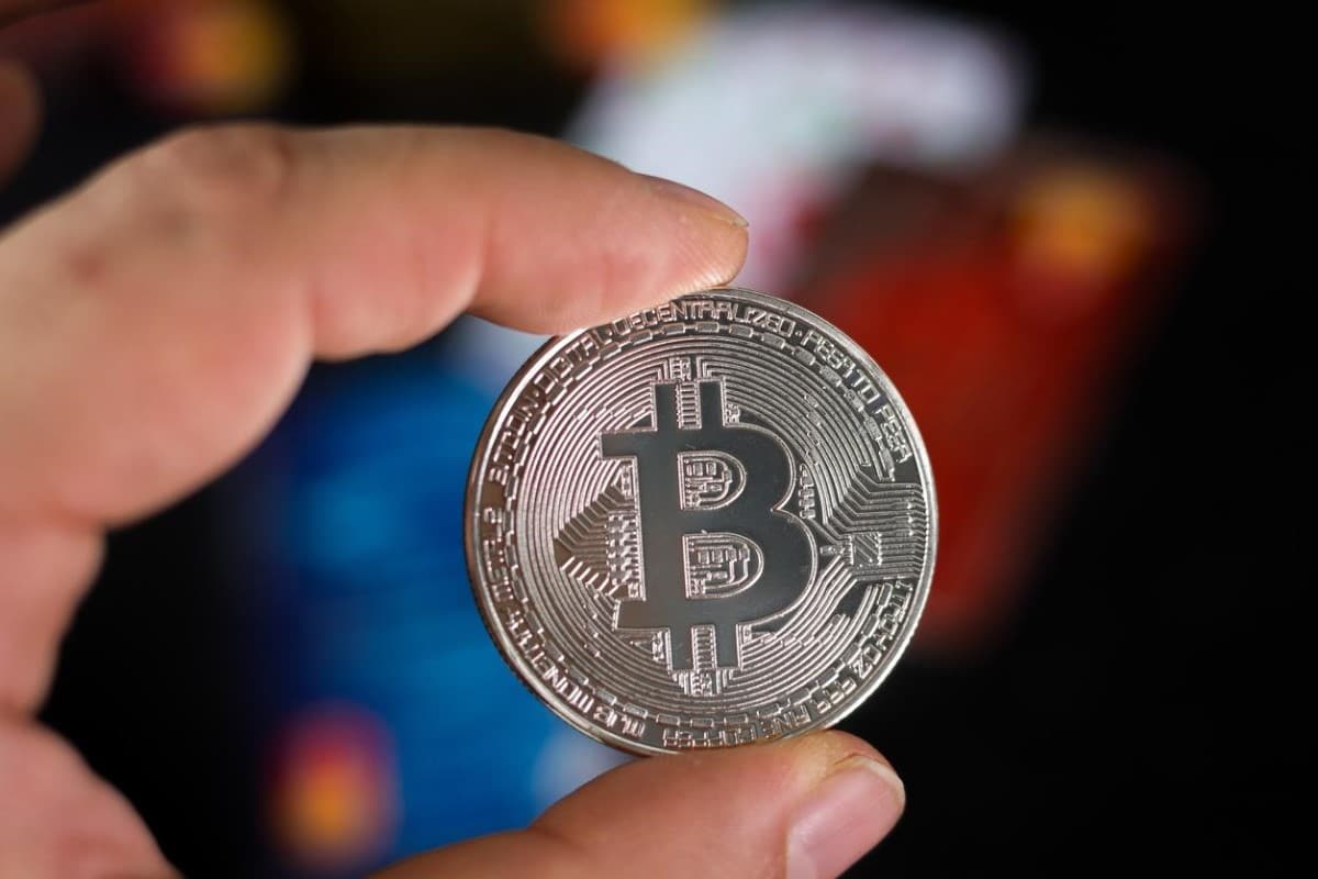 Un hombre sostiene en su mano una criptomoneda, activos ideales para inversiones a corto plazo.