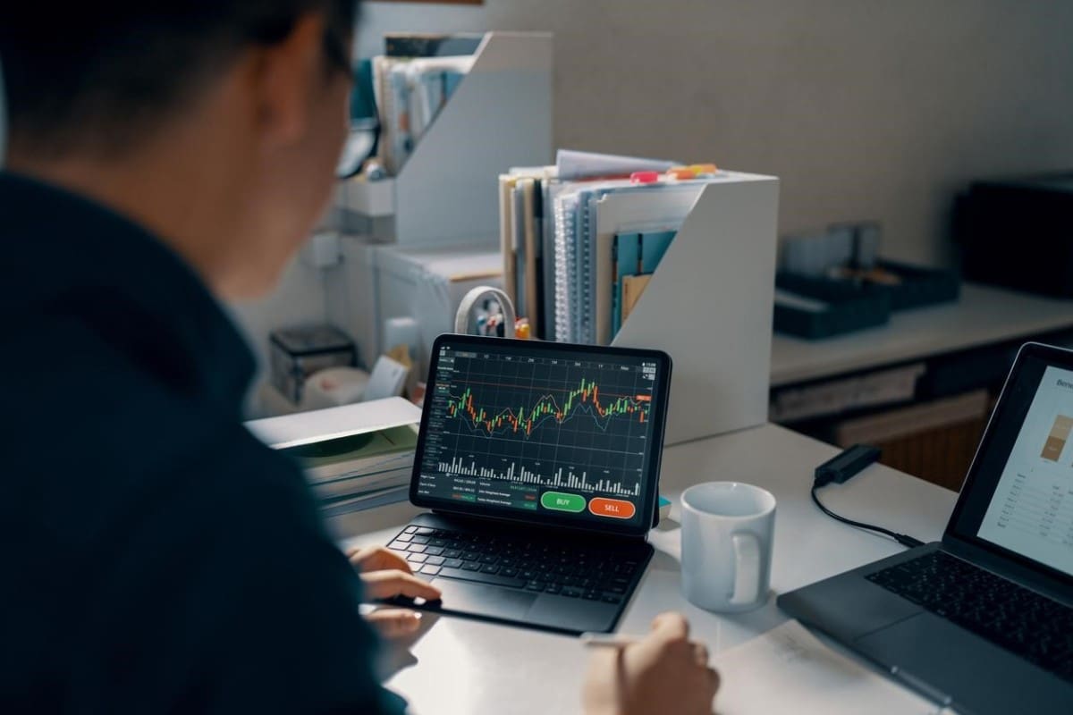 Un hombre analizando gráficas en su computadora para saber cómo invertir en divisas.