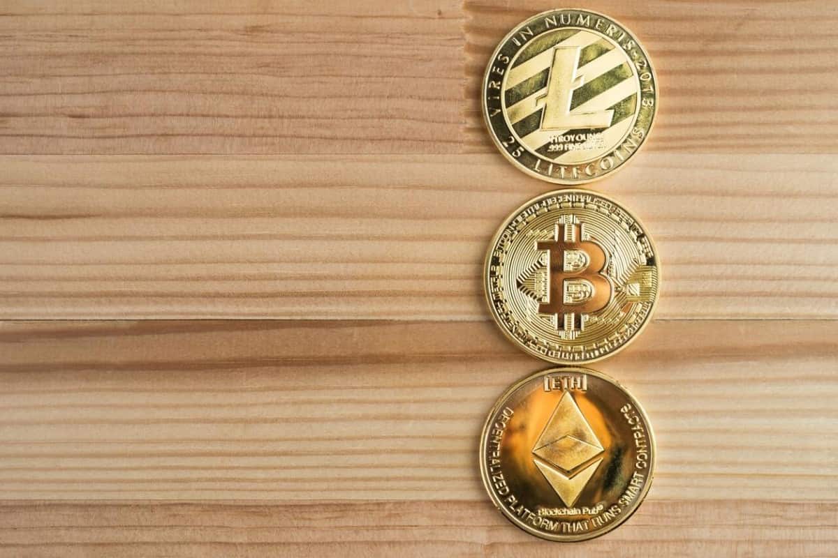 Monedas de Litecoin, Bitcoin y Ethereum sobre una superficie de madera.