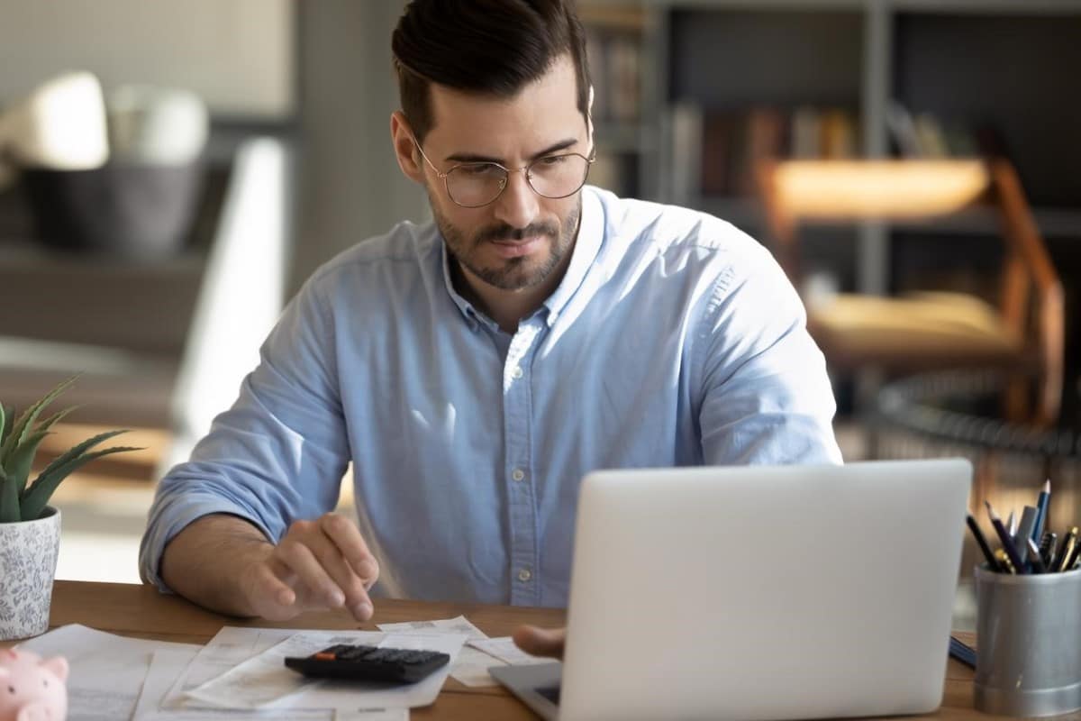 Un hombre calcula frente a su computador el margen de operación de una inversión.