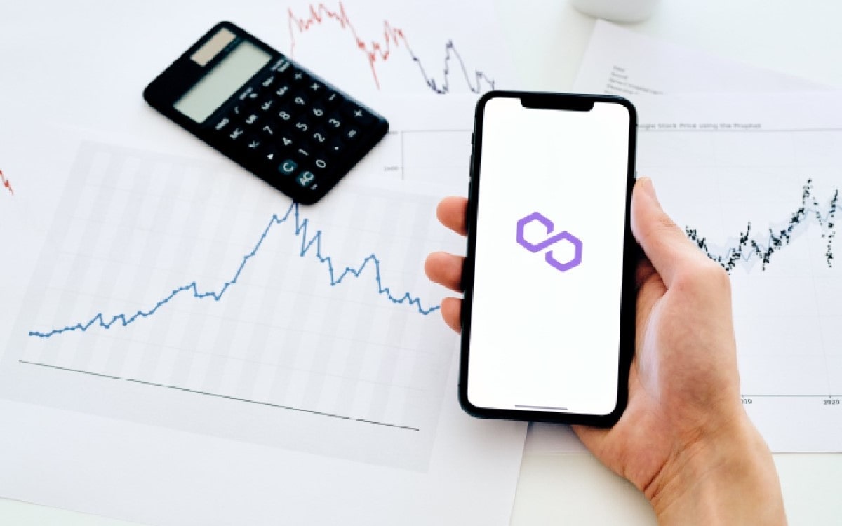 Mano sosteniendo un celular con el símbolo de Polygon.