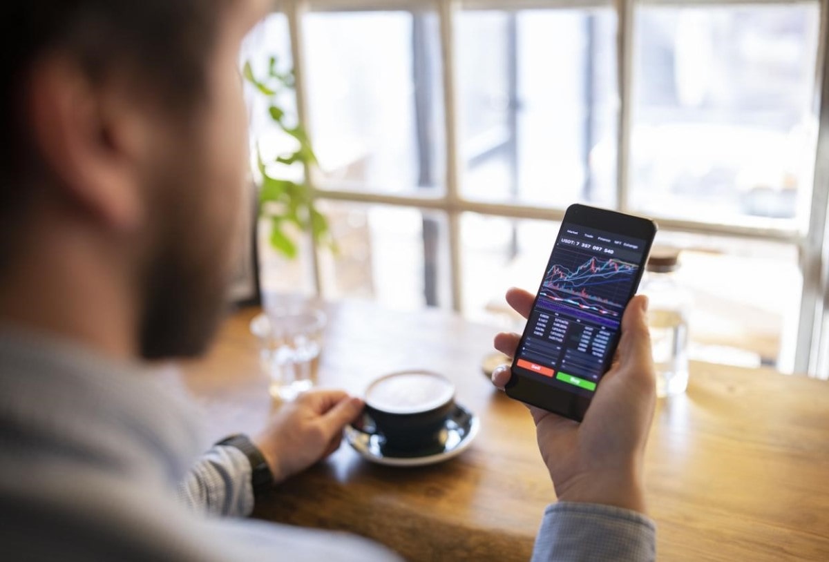 Un trader analiza en su celular tendencias sobre el precio de criptomonedas.