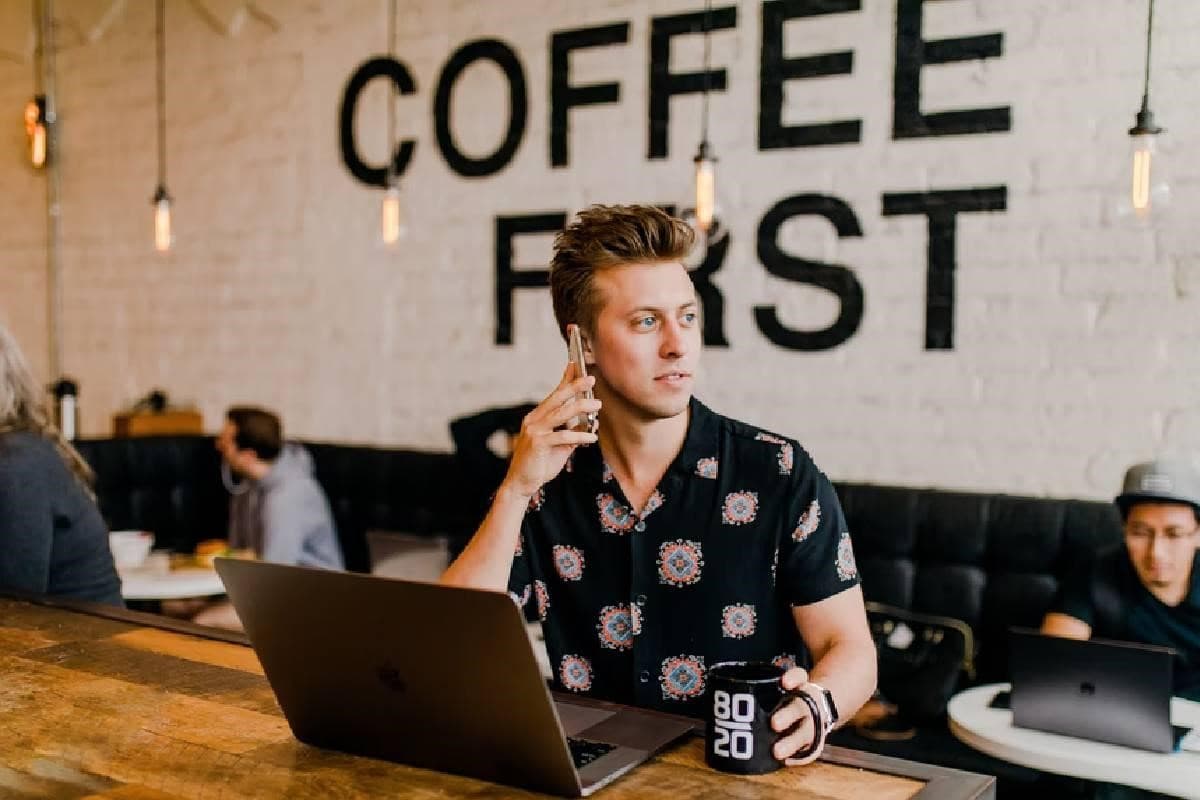 Un joven inversionista frente a su computadora y hablando por celular.