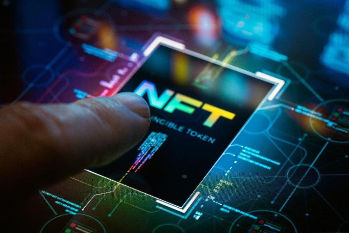 Pantalla táctil con las siglas de token no fungible. Descubre qué son los NFT.