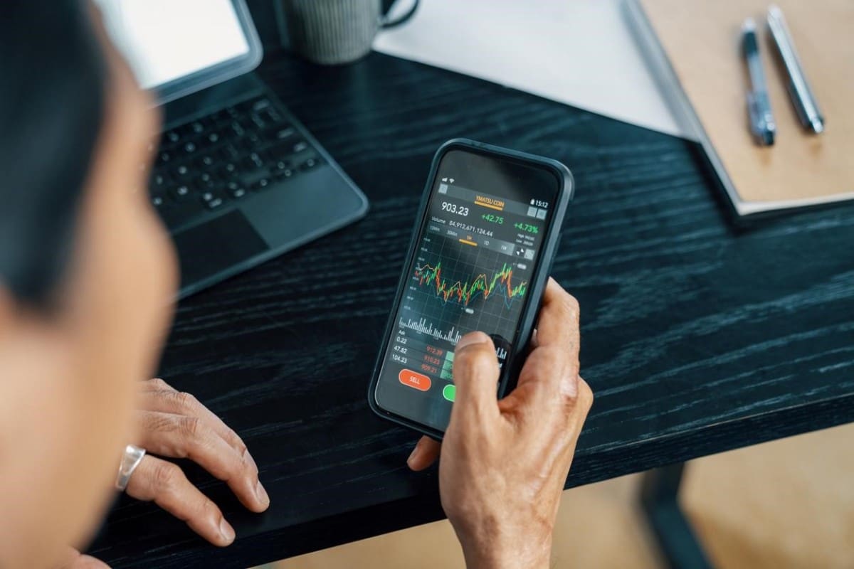 Trader compra BTC desde su celular, dado a que es seguro invertir en criptomonedas.