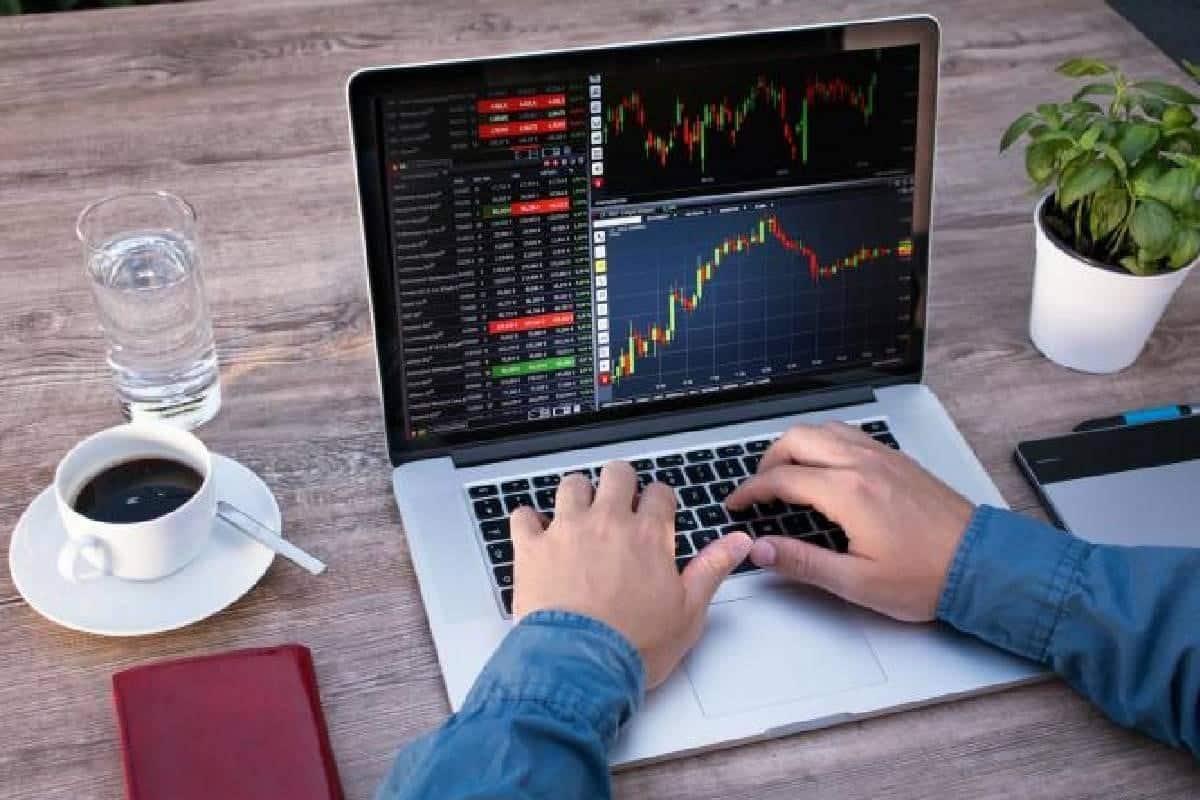 Hombre en un computador analizando gráficos sobre tendencias de criptomonedas.