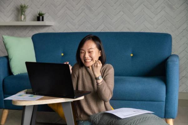 Una joven inversionista celebra frente a la computadora su libertad financiera
