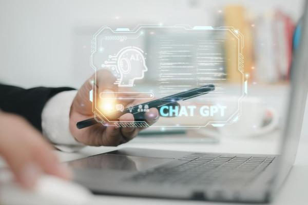 Hombre indaga en su computador y en su celular cómo funciona ChatGPT.