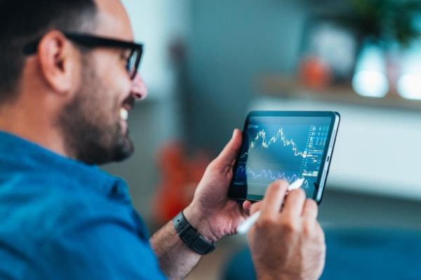 Hombre práctica trading desde su tablet. Descubre en esta nota qué es un trader.