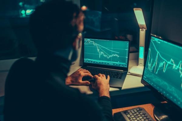 Un inversionista analiza tendencias en sus computadoras. Conoce aquí qué es drawdown.