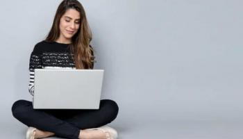 Mujer sentada con computadora para comprar acciones en Chile.