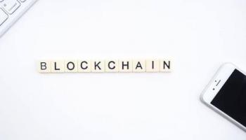 Un teclado y un celular en medio de un letrero de blockchain, tecnología en tendencia.