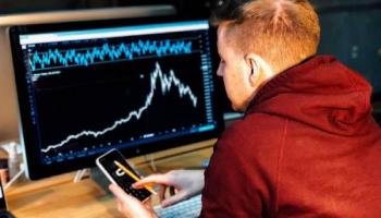 Un inversor frente a una computadora realizando análisis de precio de un activo.
