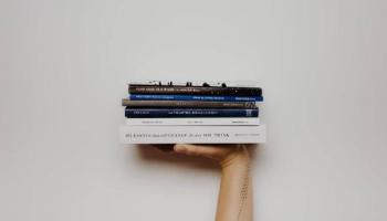 Una mano sosteniendo varios libros de trading.