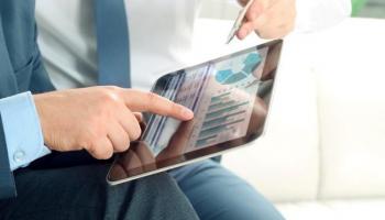 Dos hombres analizan gráficos en una tablet para saber cómo invertir en S&P500.