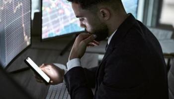 Un trader revisa cotizaciones en su celular. Conoce en esta nota qué es el fomo en trading