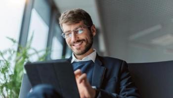 Empresario sonríe frente a su tablet mientras negocia swaps.