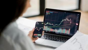 Una inversionista analiza datos de la bolsa de valores desde sus dispositivos móviles.