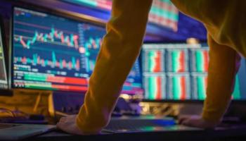 Trader revisa gráficos en sus monitores y analiza si abrir una orden Buy Limit.