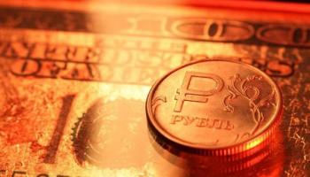 Una moneda de un rublo ruso sobre un billete de 100 dólares estadounidenses. 