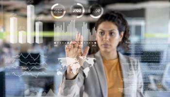 Una mujer revisa gráficos en una pantalla interactiva. Conoce el impacto de la inteligencia artificial en la economía.